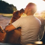 a man embracing with his dog in a parked car at sunset