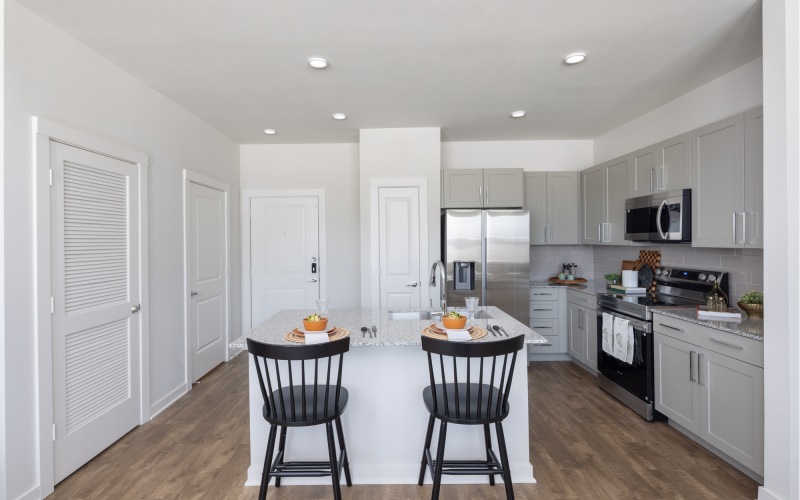 Kitchen with Island and Smart Stainless Steel Appliances and Bar Stools